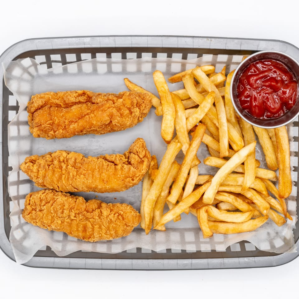 Basket of three crispy fried chicken tenders with golden fries and a cup of ketchup.