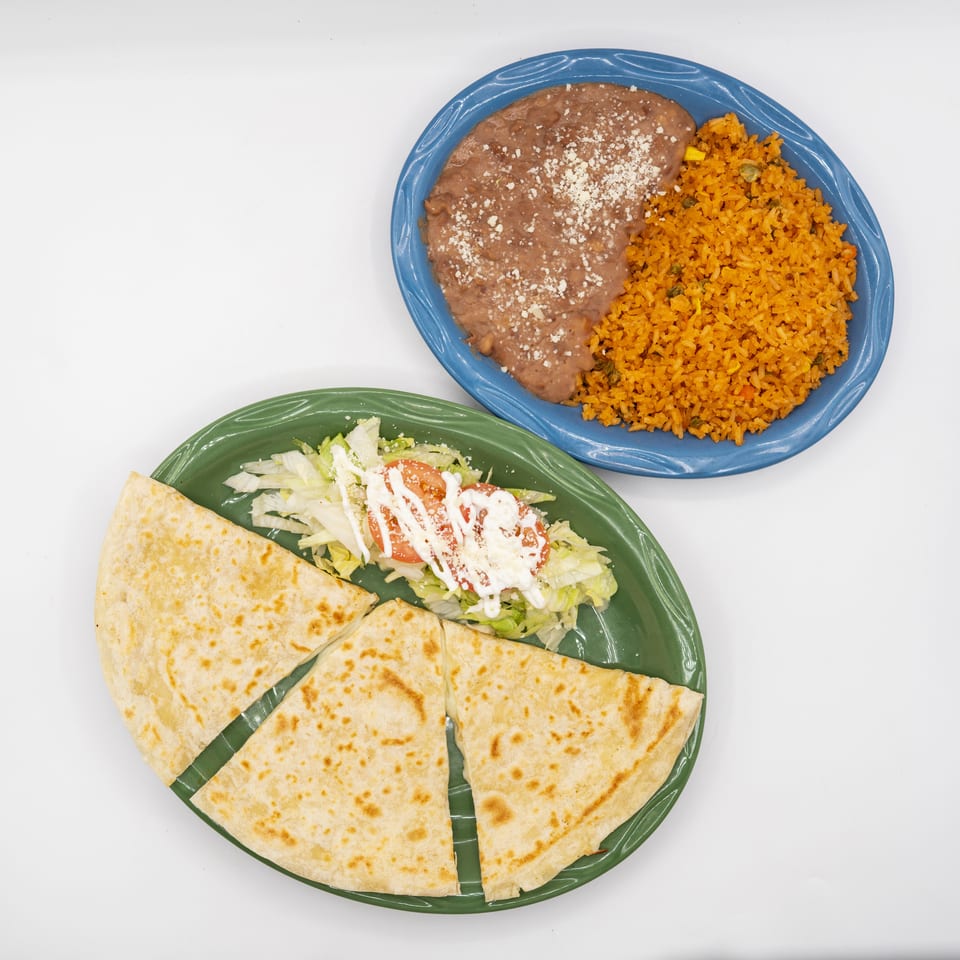 Mexican meal featuring refried beans, orange rice, quesadilla wedges, and lettuce salad topped with tomatoes, cheese, and sour cream.